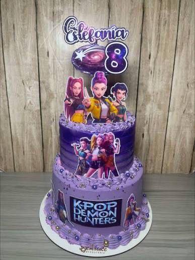 Two-tier purple birthday cake themed with K-Pop Demon Hunters decorations and custom name and age cake topper.