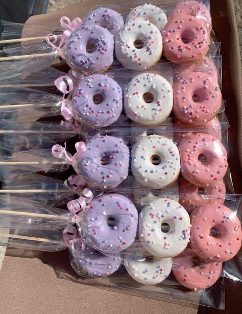 Individually wrapped purple, white, and pink glazed donut pops on sticks with pastel sprinkles