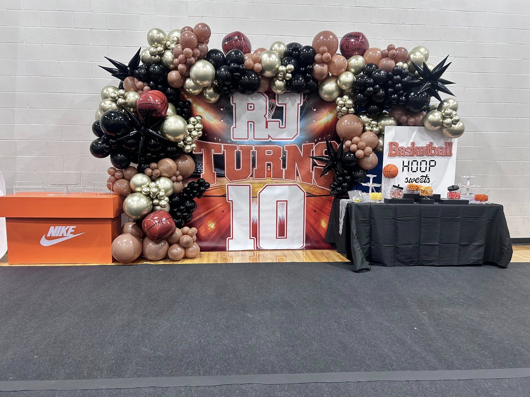 Basketball-themed 10th birthday party display with custom backdrop, balloon arch, and dessert table.