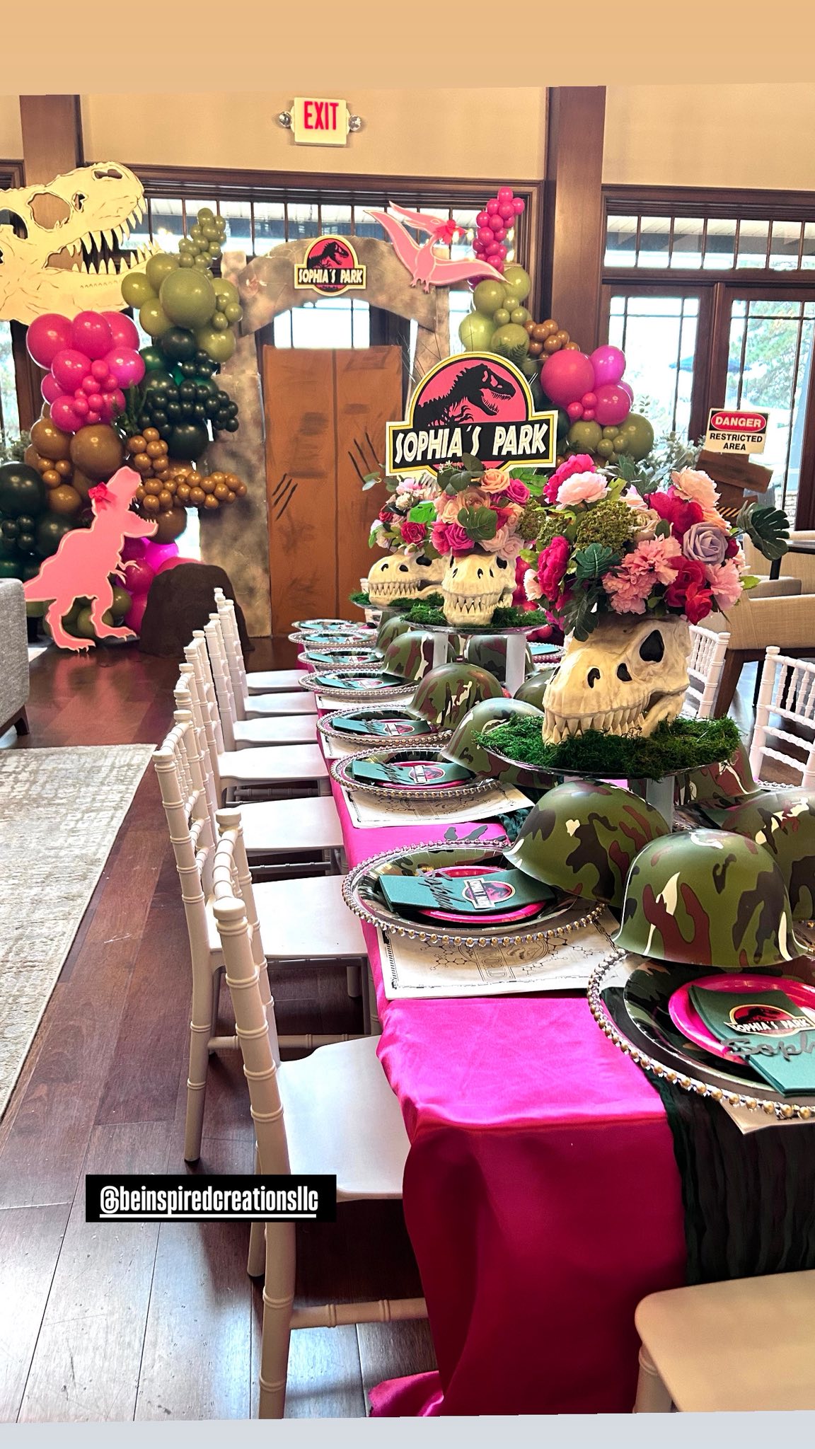 Table set for a Sophia's Park dinosaur-themed party with skull centerpieces, camo helmets, and pink decor.