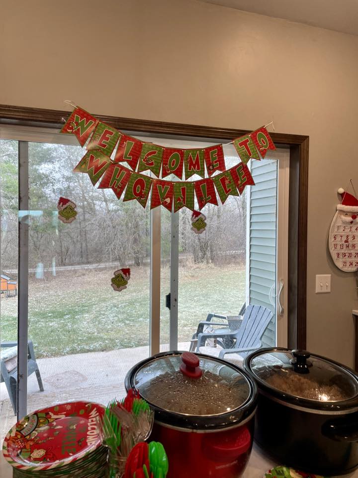 Welcome to Whoville Christmas banner hanging above a sliding glass door surrounded by Grinch themed decor.
