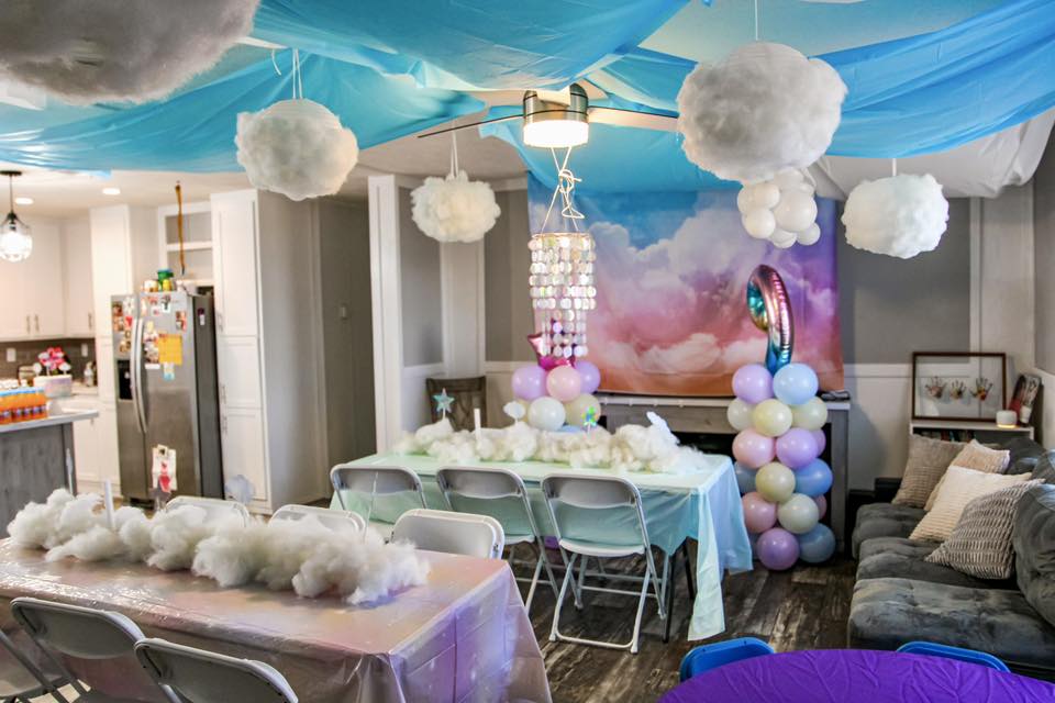Living room decorated for a themed party with blue ceiling draping and fluffy cloud decorations.