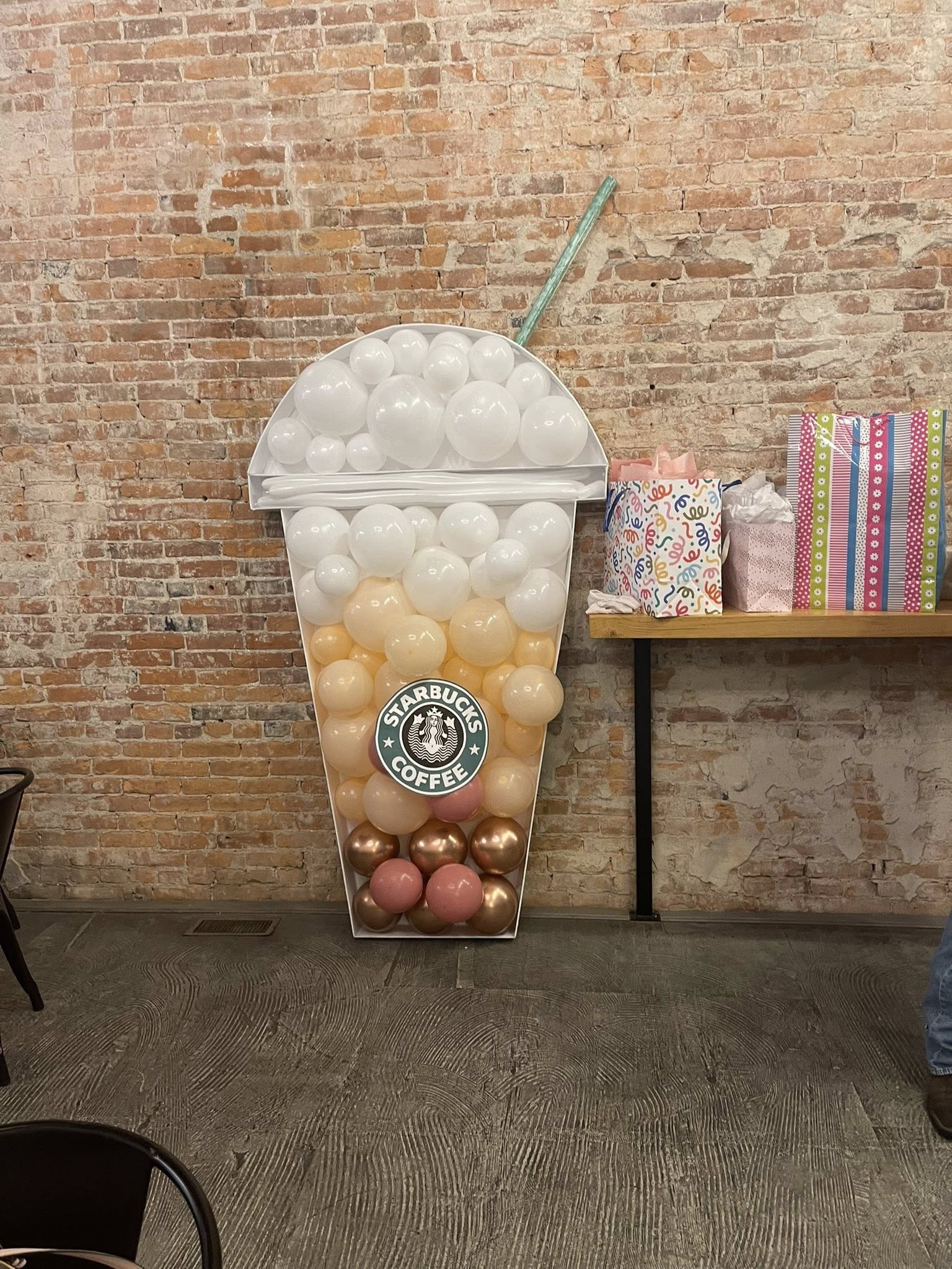 Starbucks inspired coffee cup balloon mosaic decoration standing against a brick wall.