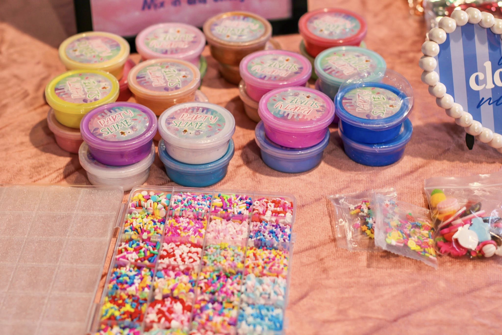 Colorful containers of party slime with a plastic kit of small decorative beads and sprinkles.
