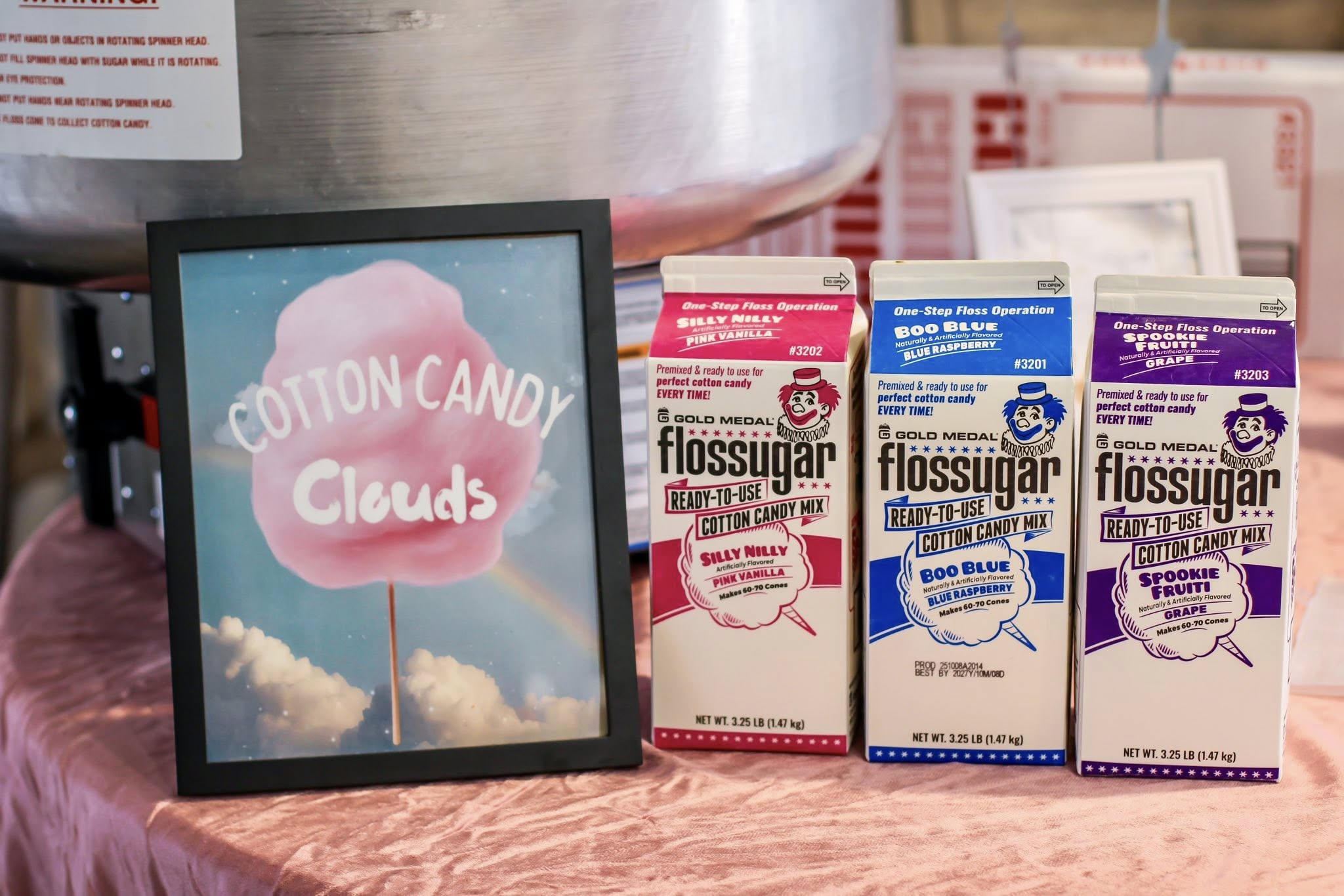 Three cartons of Gold Medal Flossugar cotton candy mix in pink vanilla, blue raspberry, and grape.