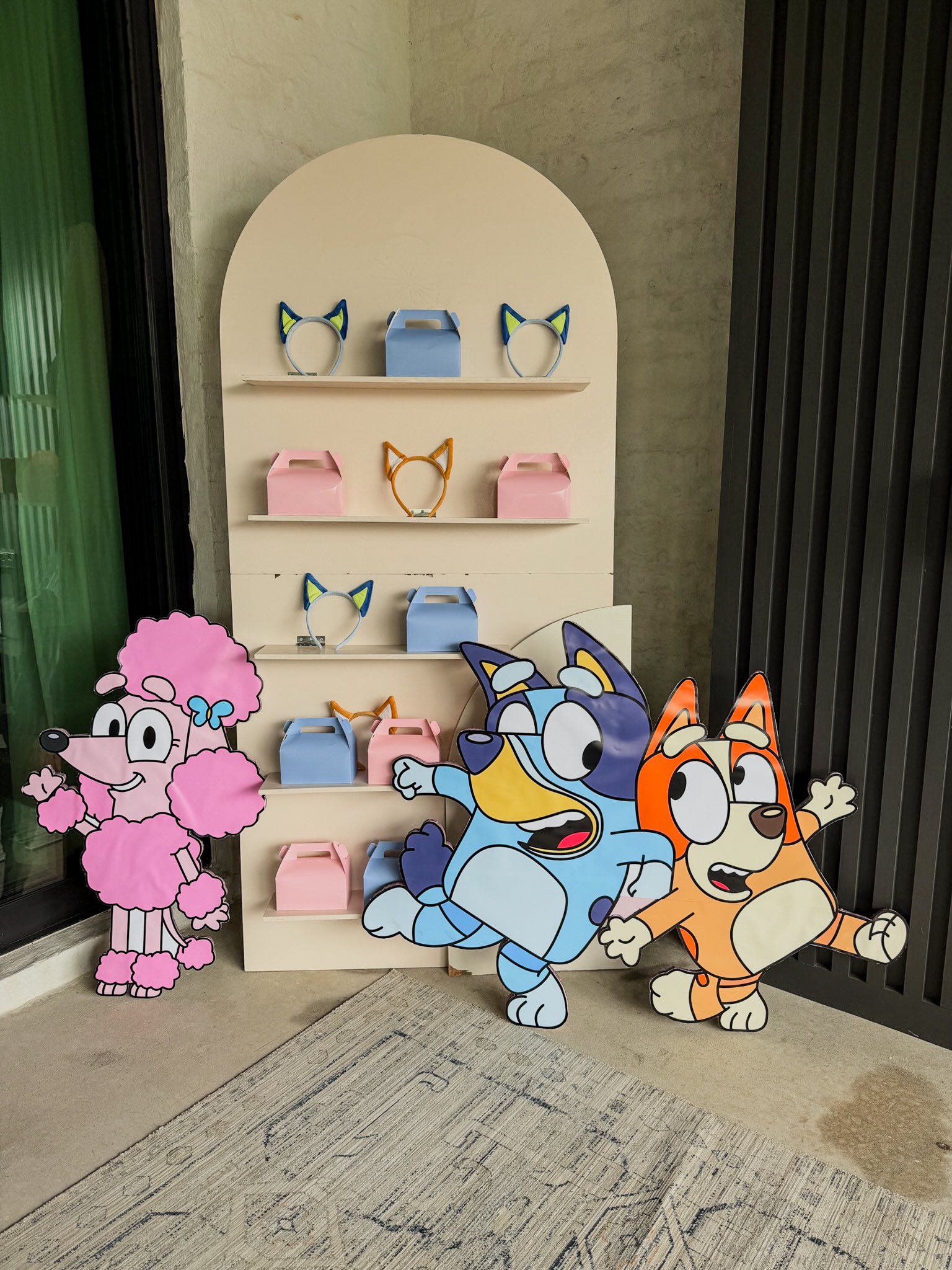 Bluey and Bingo themed party display shelf with party favor boxes and animal ear headbands.
