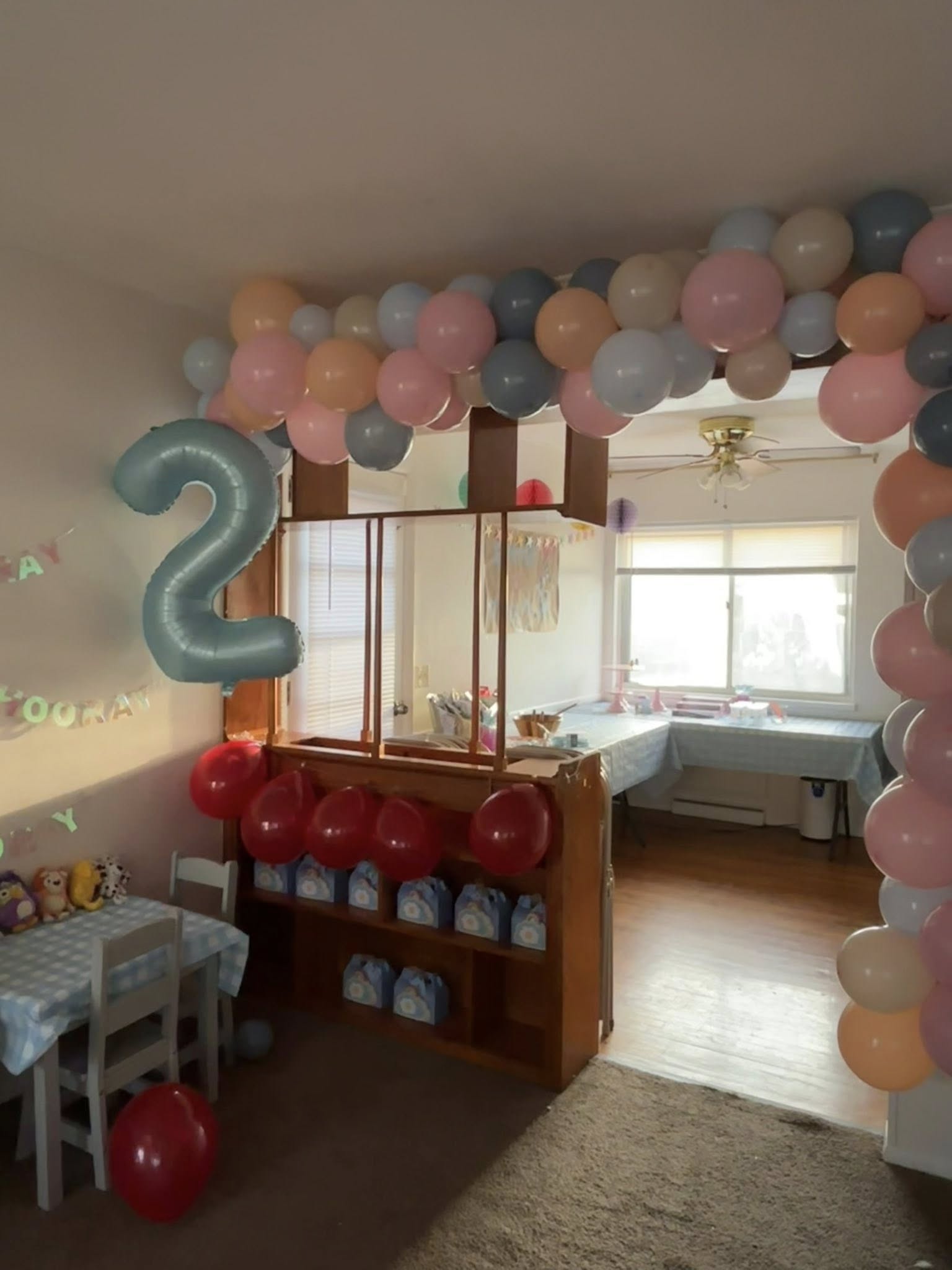 Decorated room for a 2nd birthday party featuring a balloon arch and light blue '2' balloon.