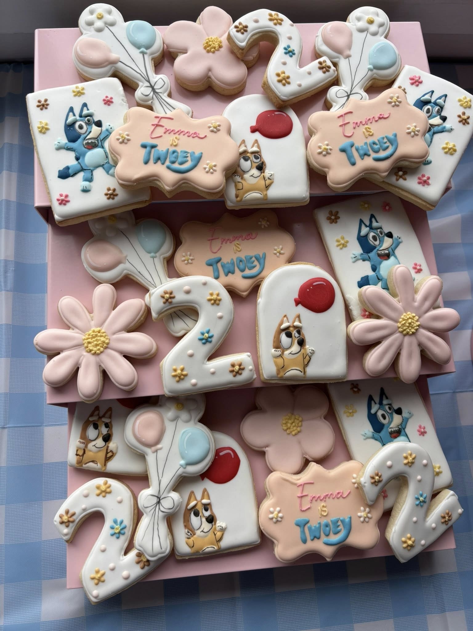 Assorted Bluey-themed sugar cookies for a second birthday, featuring number 2s, flowers, balloons, and character designs.