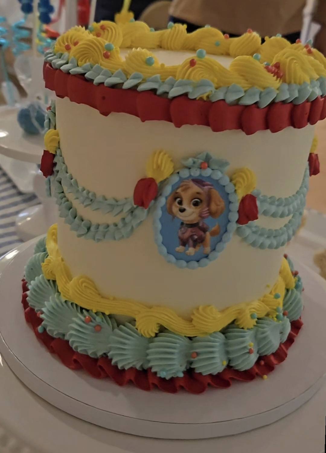 Paw Patrol Skye themed birthday cake with blue, yellow, and red buttercream piping decorations