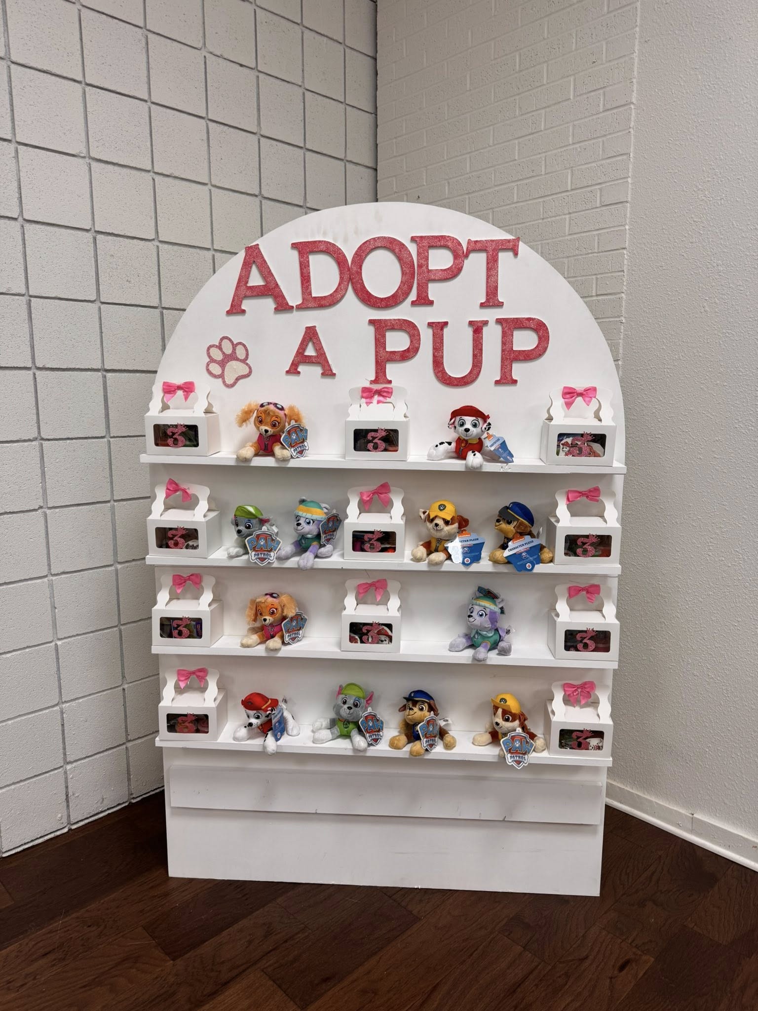 Adopt a Pup display stand with Paw Patrol plushies and small party favor boxes.