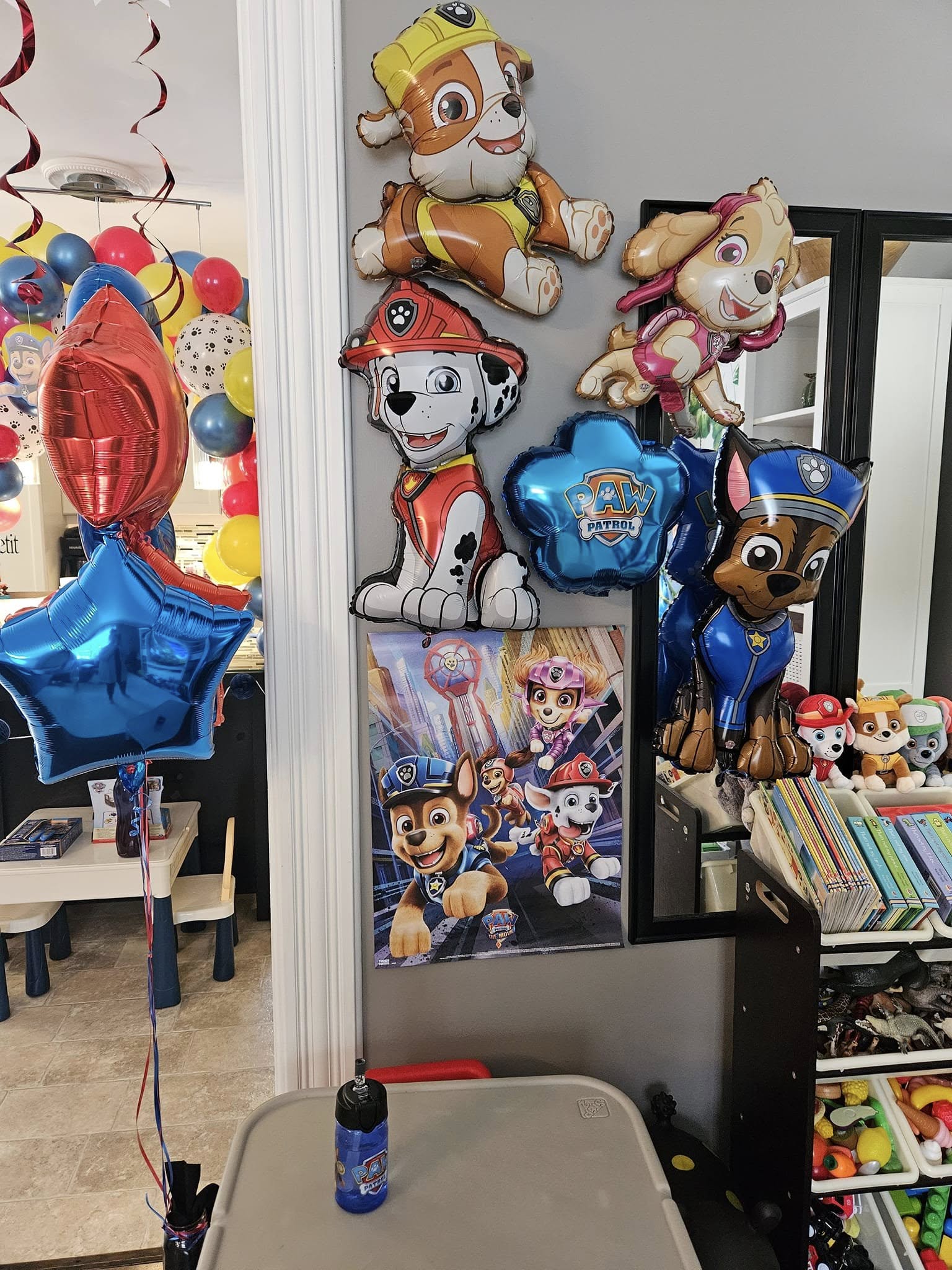 Paw Patrol themed birthday decorations including balloons of Rubble, Skye, Marshall, and Chase on a wall
