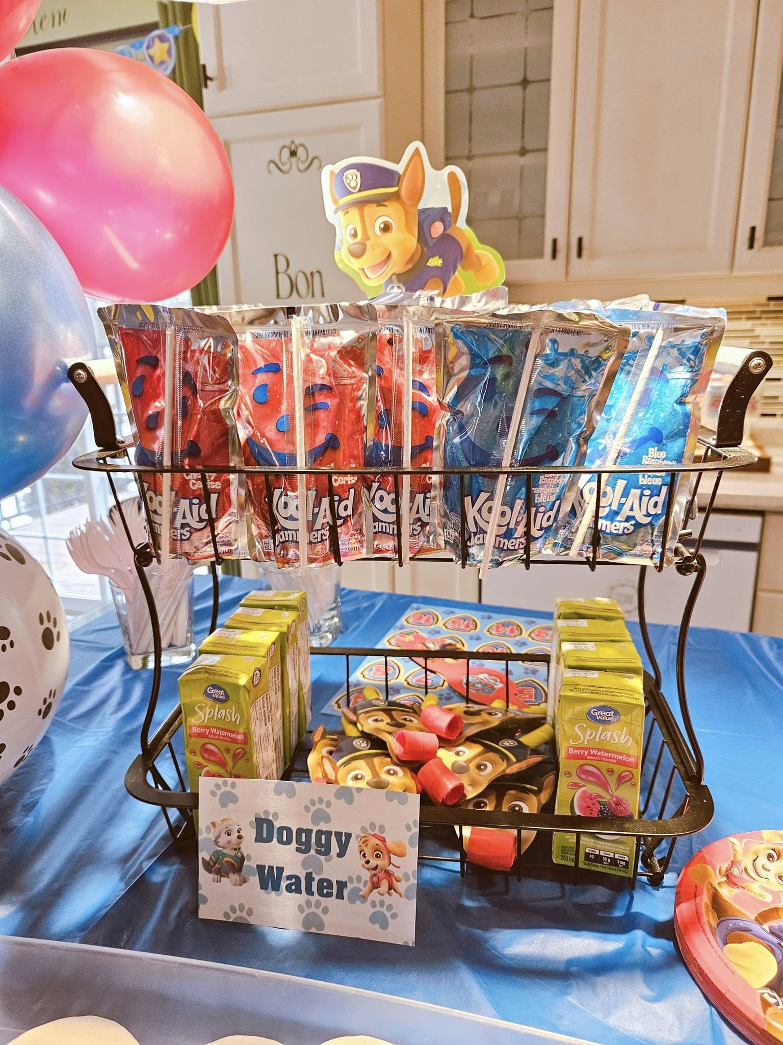 Two-tier metal rack filled with Kool-Aid Jammers and Great Value juice boxes at a Paw Patrol themed party