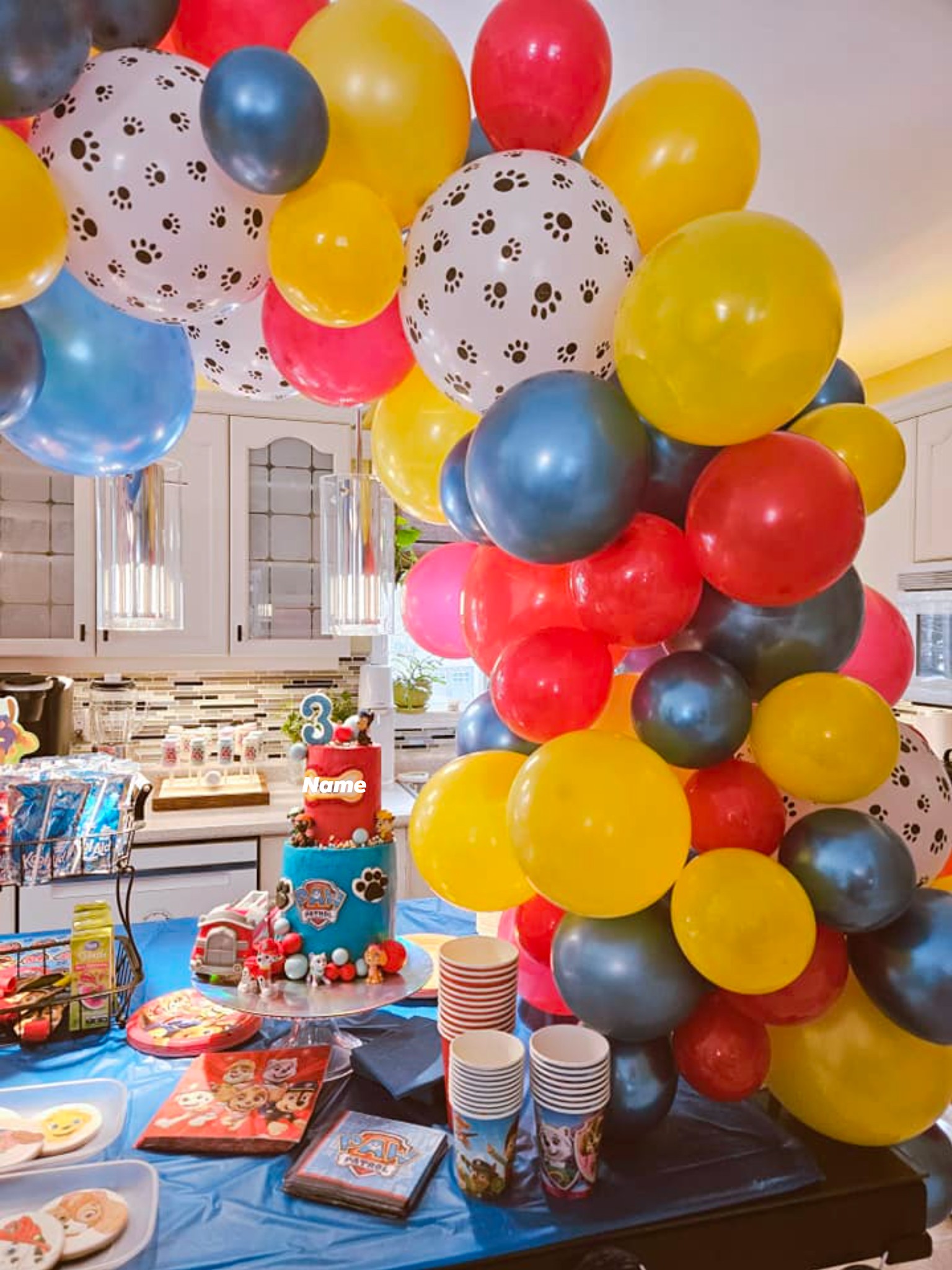 Paw Patrol themed birthday birthday cake with a number 3 topper surrounded by colorful party balloons