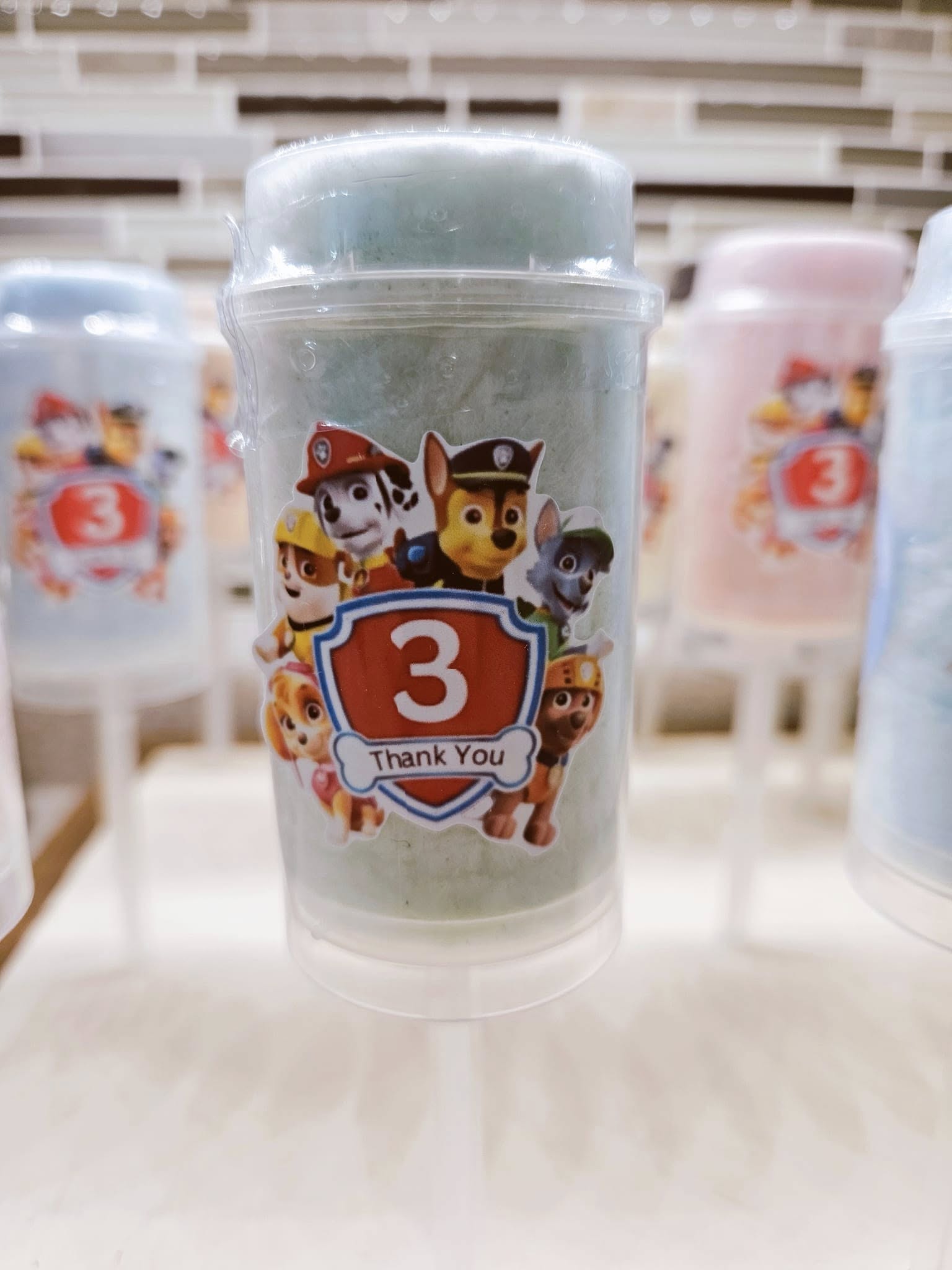 Paw Patrol themed party favor cotton candy container with a thank you label and age three birthday emblem.