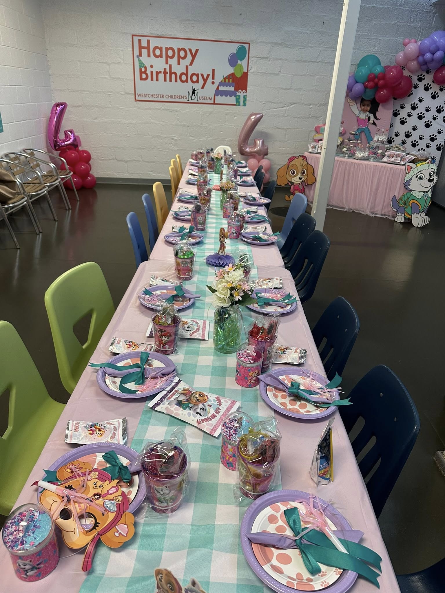 Paw Patrol themed kids party table set up at Westchester Children's Museum with pink and teal decorations.