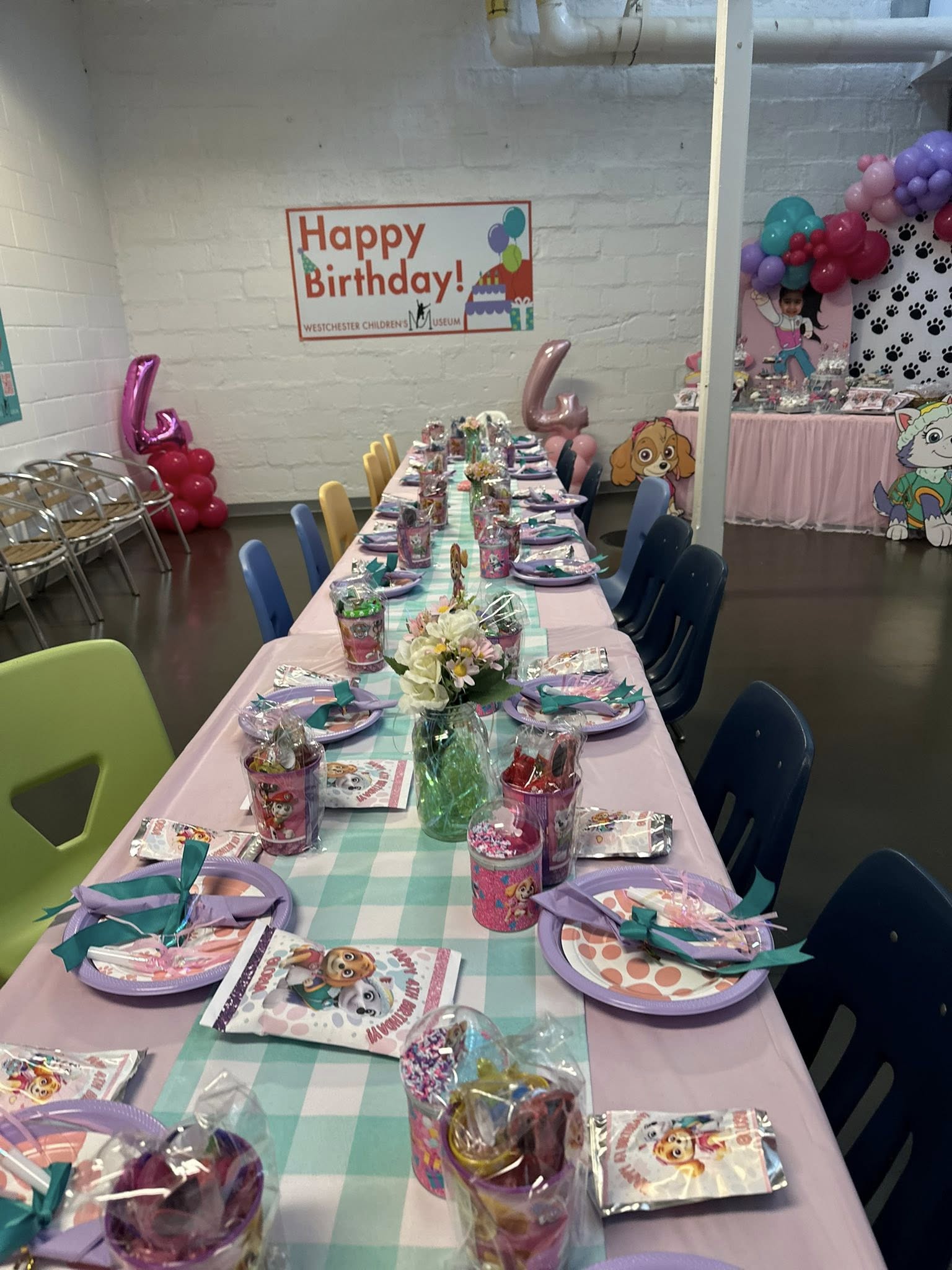 Table set for a fourth birthday party at Westchester Children's Museum with Paw Patrol themed decorations.