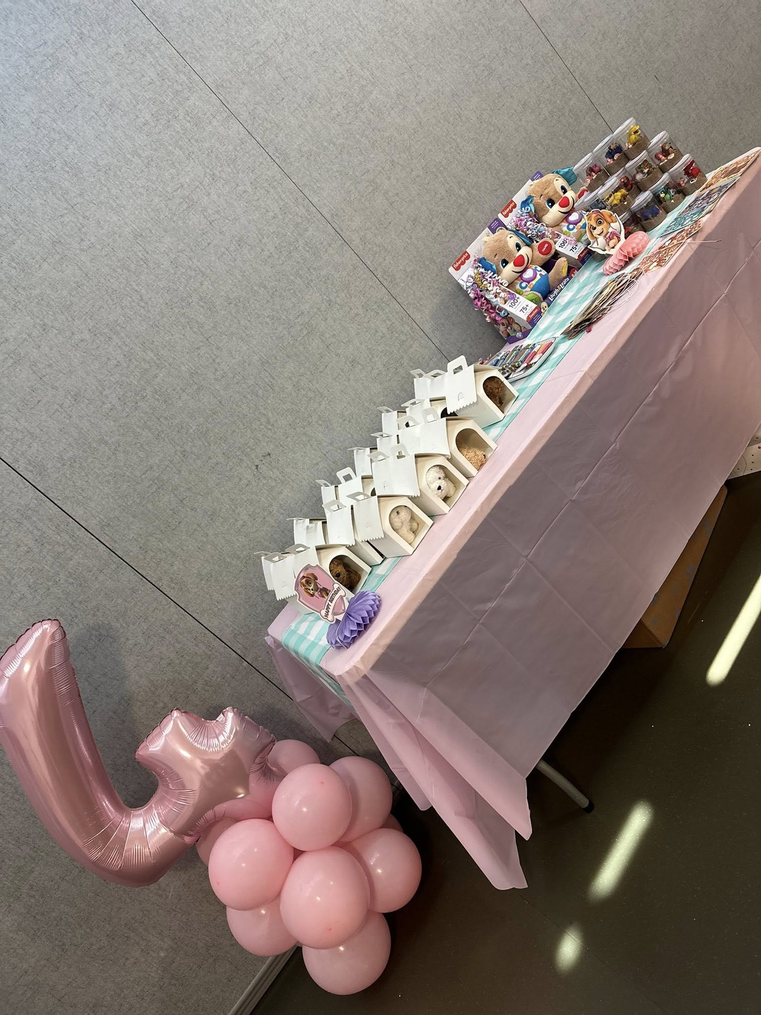 Table decorated for a child's birthday party with small dog plush party favors and Fisher-Price toy boxes.