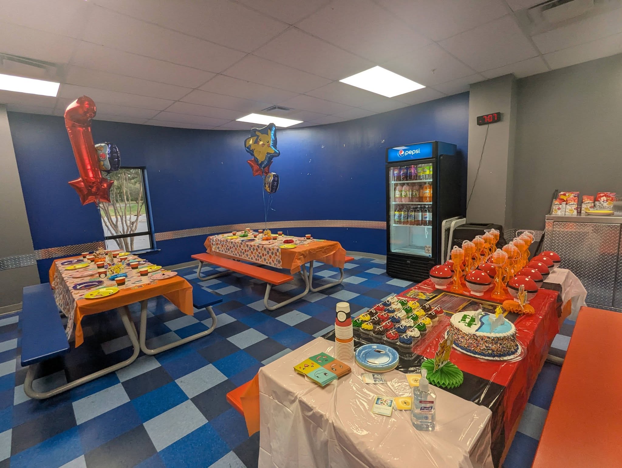 Pokemon themed birthday party room with decorated tables featuring plates, cups, and a cake.