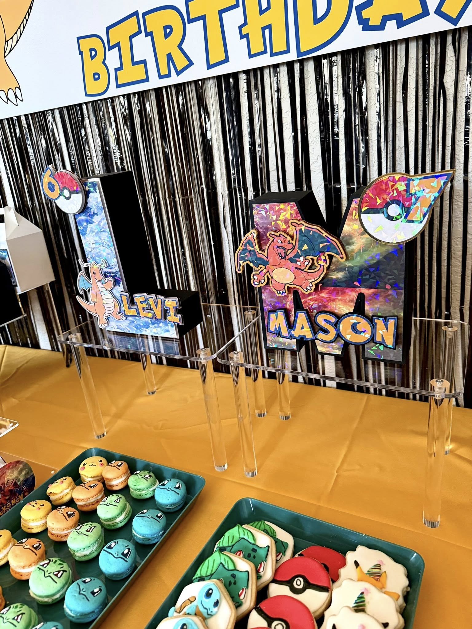 Table display with personalized Pokemon letter signs for Levi and Mason and Pokemon themed macarons and cookies