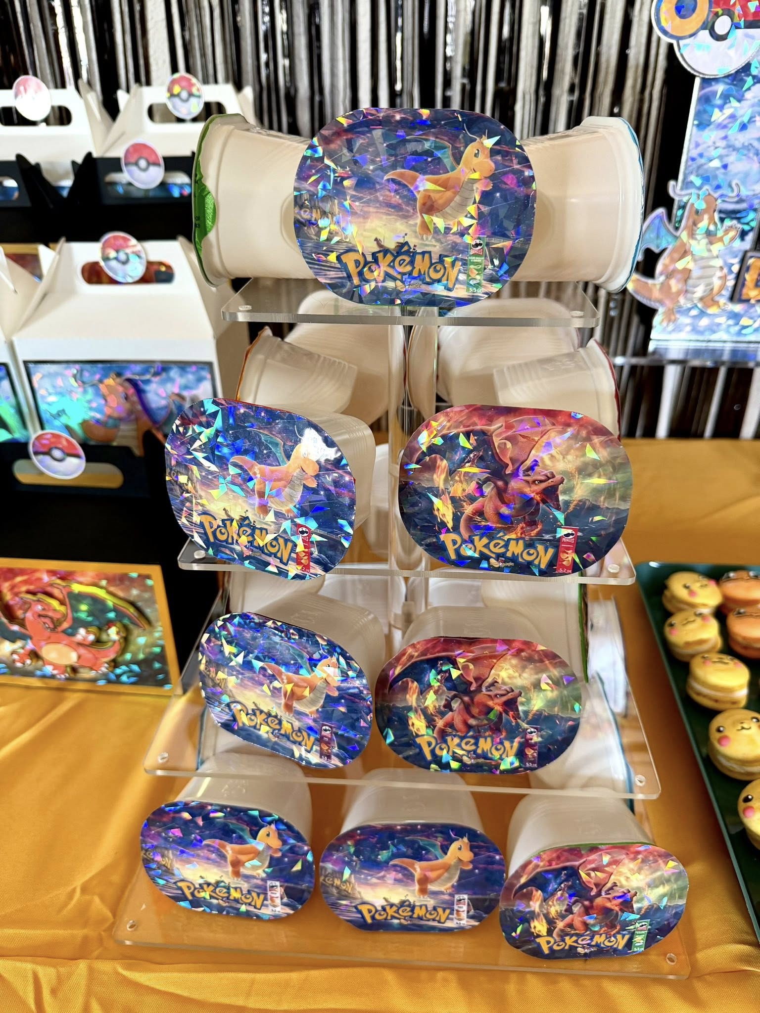 Display stand featuring holographic Pokemon-themed Pringles cans with Charizard and Dragonite artwork