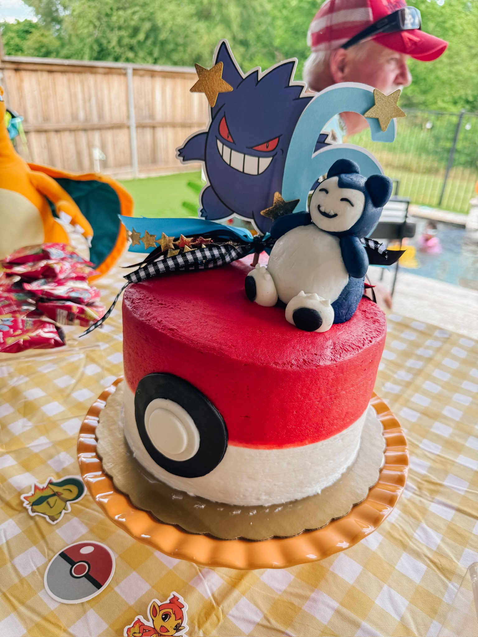 Pokemon themed birthday cake with a poke ball design, Gengar topper, and a Snorlax figure for a sixth birthday.