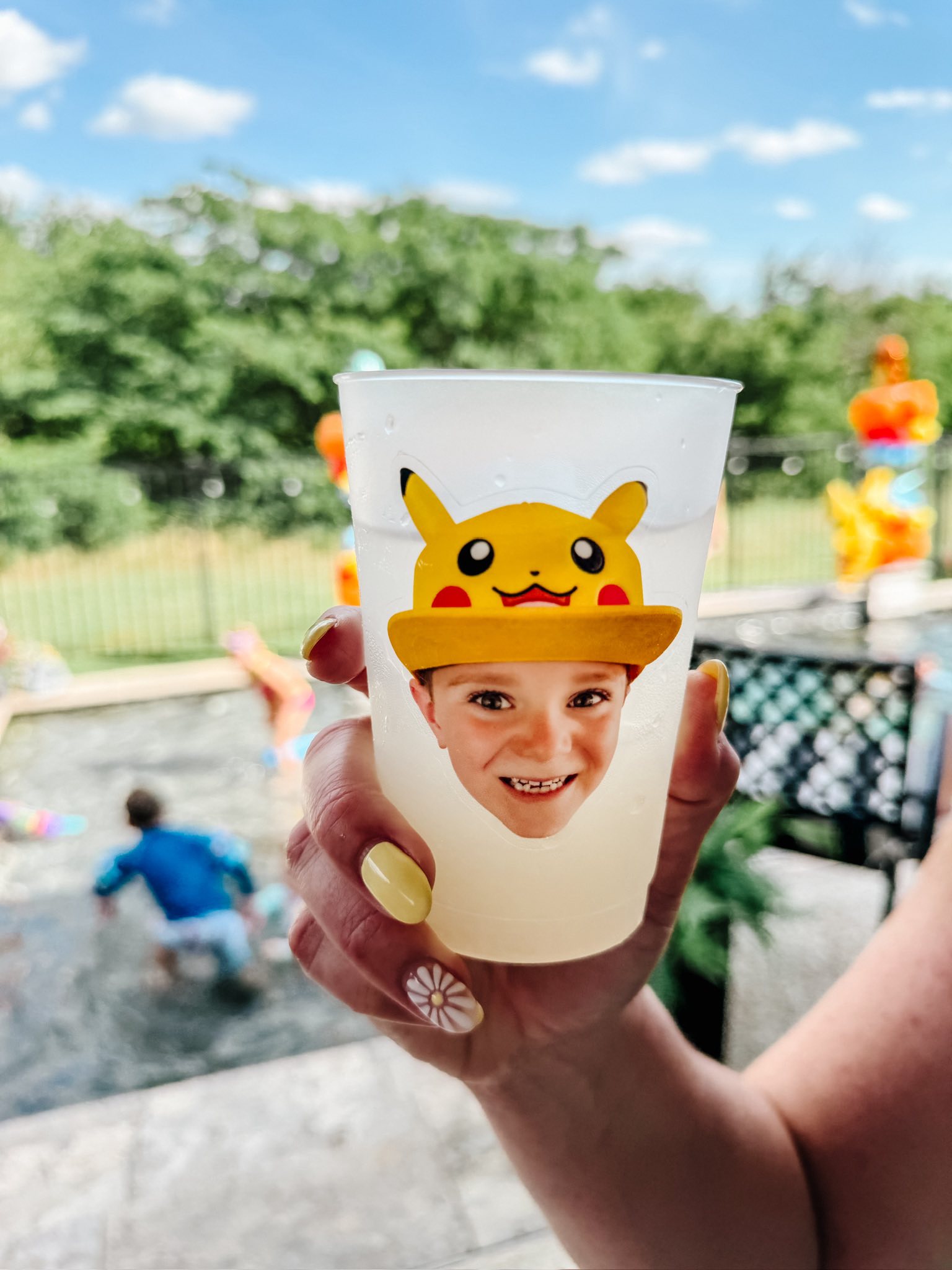 Custom party cup featuring a child's face wearing a Pikachu hat over a backyard pool scene