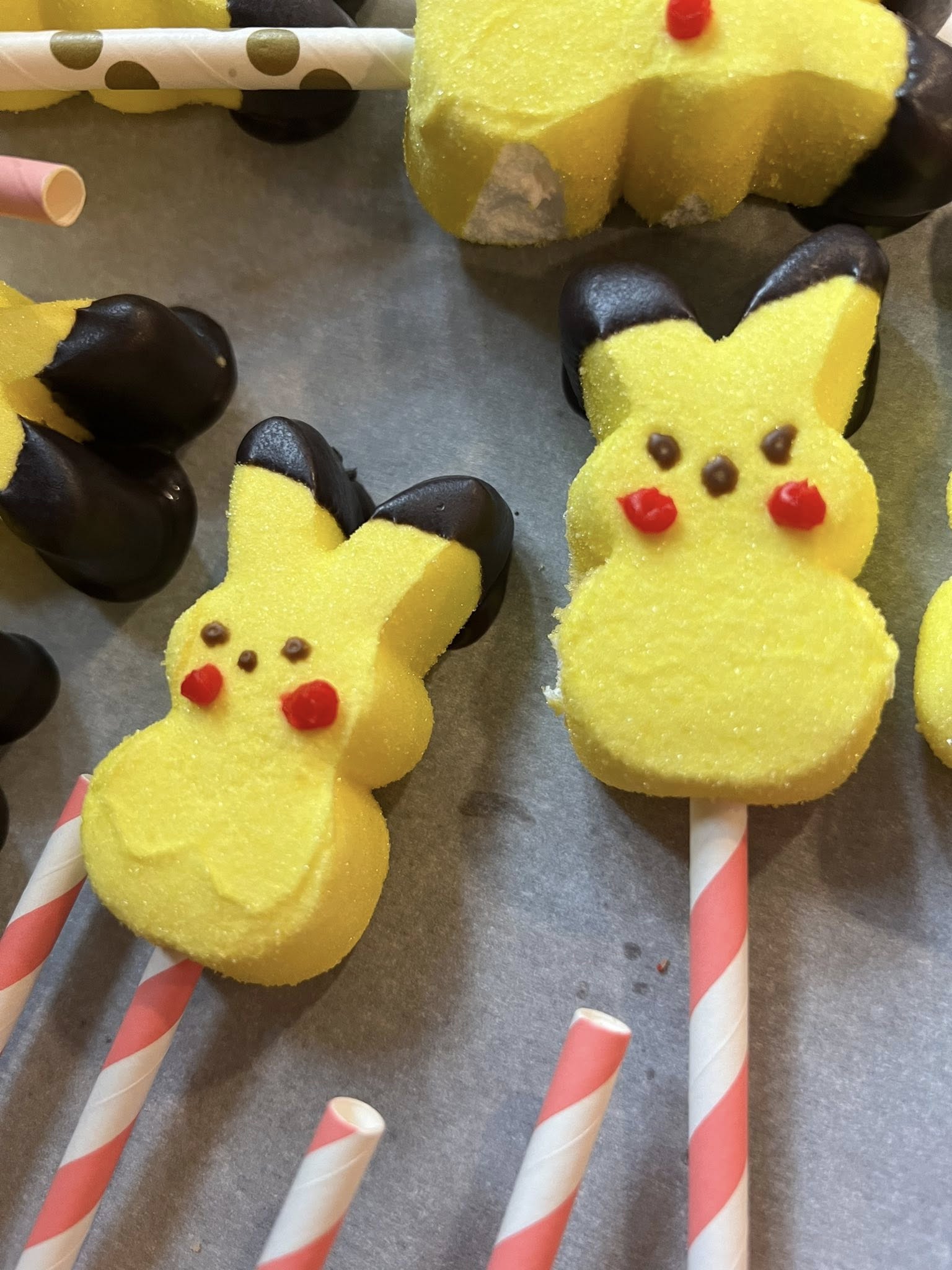 Pikachu-themed marshmallow peep pops decorated with chocolate ears on striped paper sticks