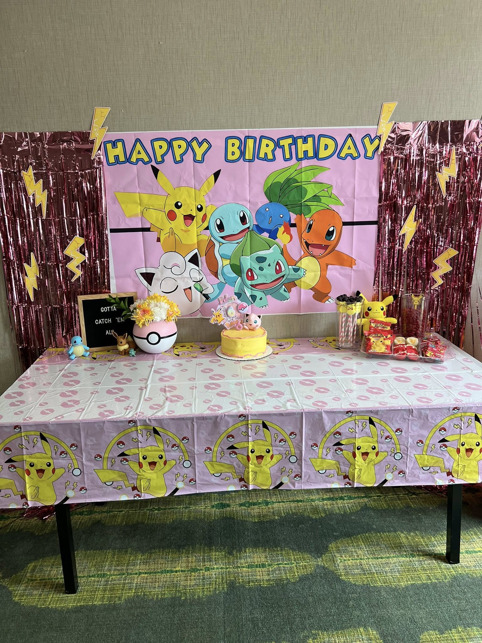 Pokemon themed birthday party table setup with a cake, party snacks, and Pikachu decorations.