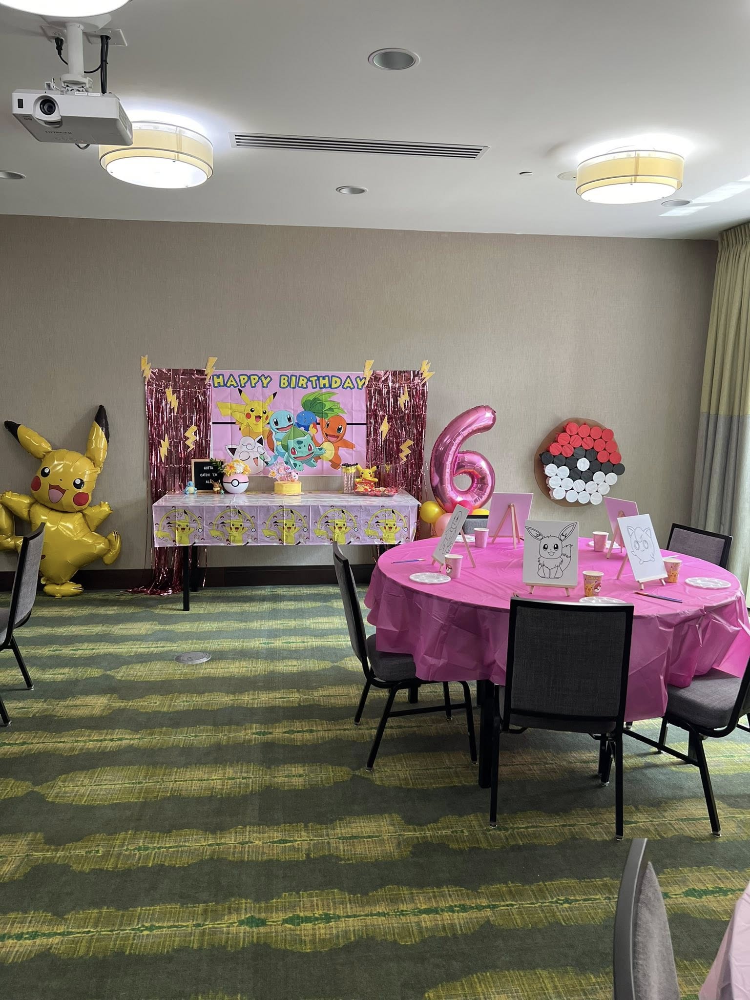 Pokemon themed birthday party decoration setup with a birthday table, Pikachu balloon, and creative activity area.