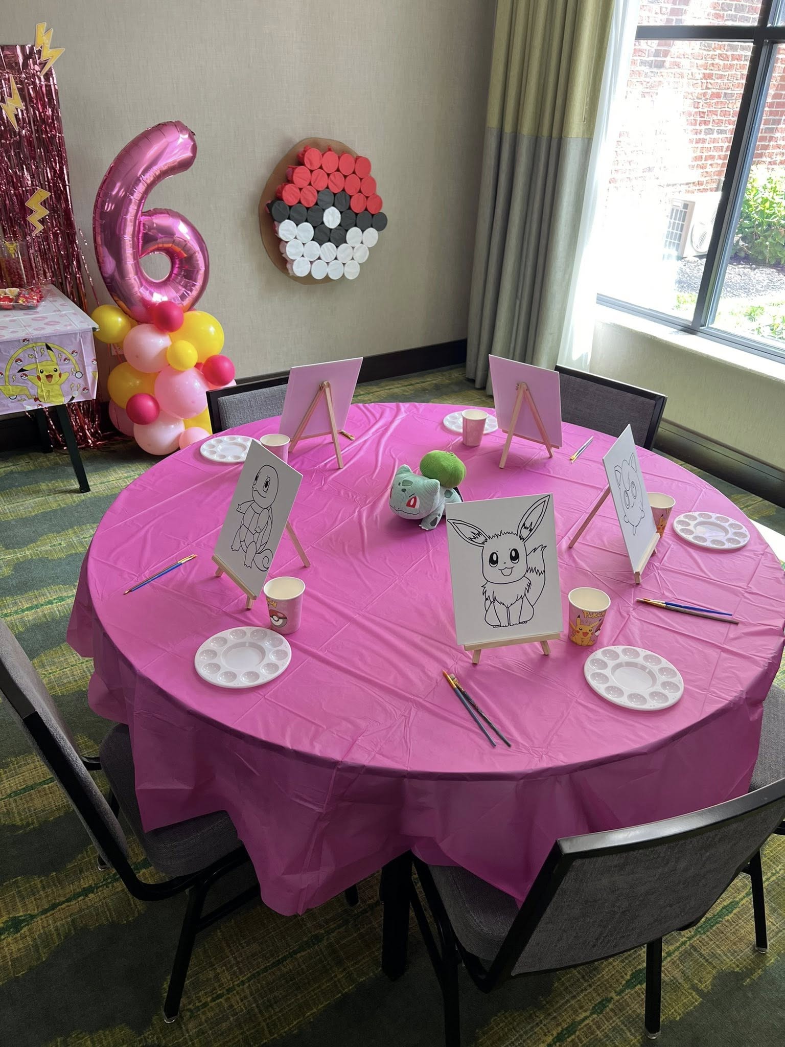Table set up for a Pokemon-themed birthday paint party with canvases, palettes, and brushes.