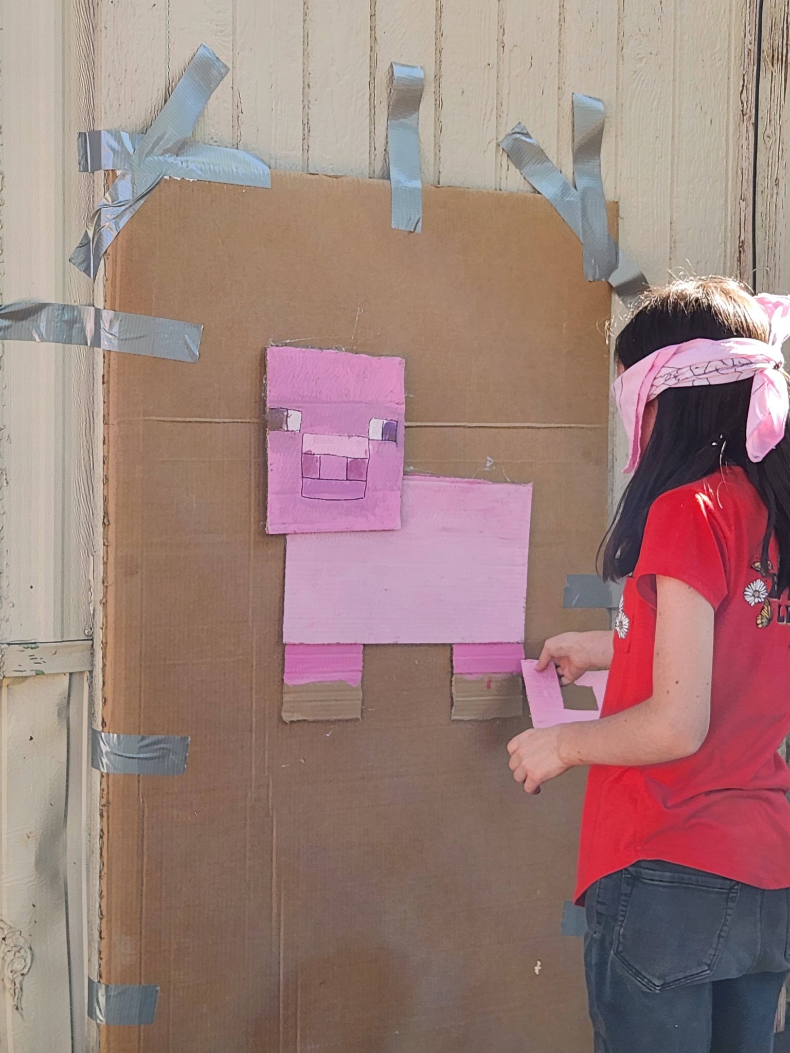 Child playing a pin the tail on the Minecraft pig game at a birthday party.