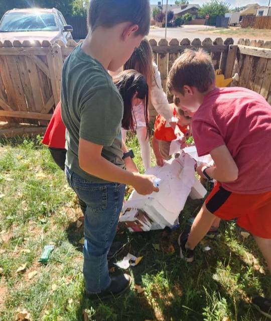 Group of children playing together with a craft project in a sunny backyard.