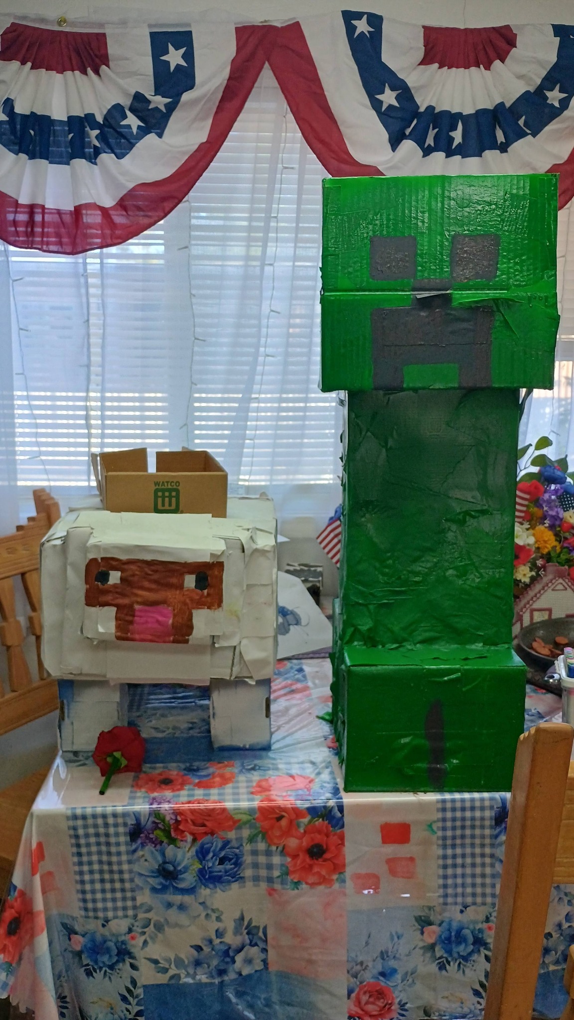 DIY Minecraft Creeper and sheep figures made from cardboard boxes on a table.