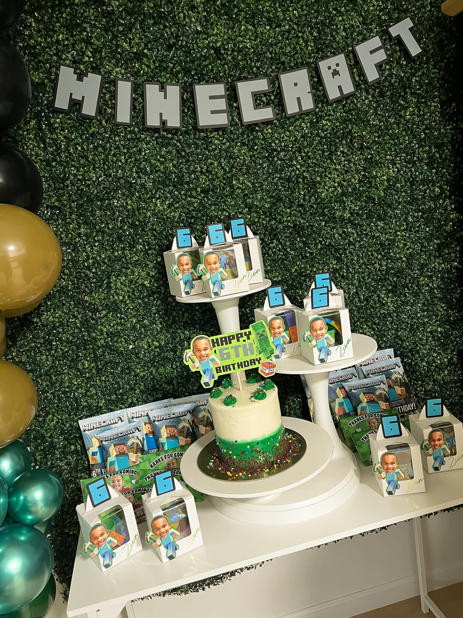 Minecraft themed 6th birthday party setup with themed cake, party favor boxes, and green grass decorated backdrop.