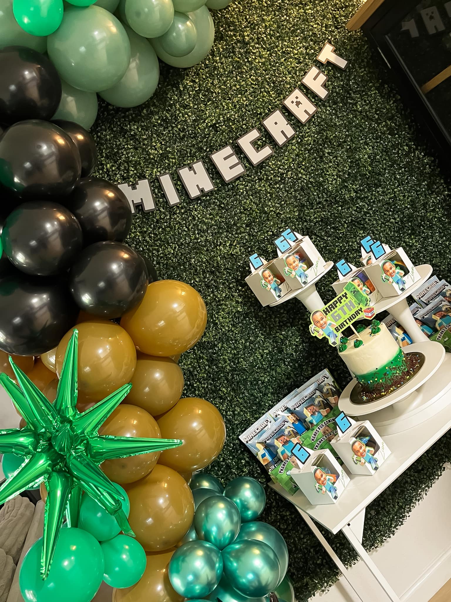 Minecraft-themed 6th birthday party setup with balloon garland, custom favor boxes, and a decorated cake.