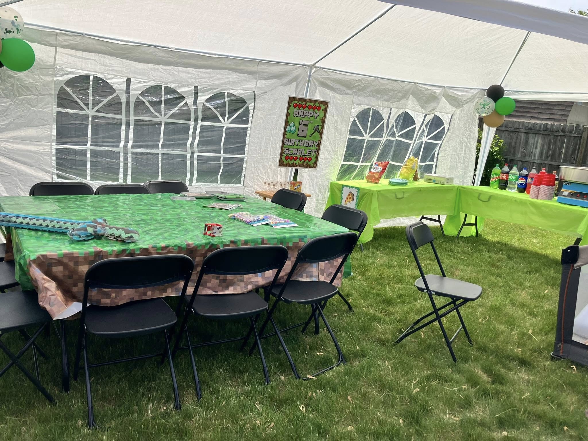 Minecraft-themed outdoor party setup with green pixel tablecloths, black chairs, and a Happy Birthday Scarlet sign.