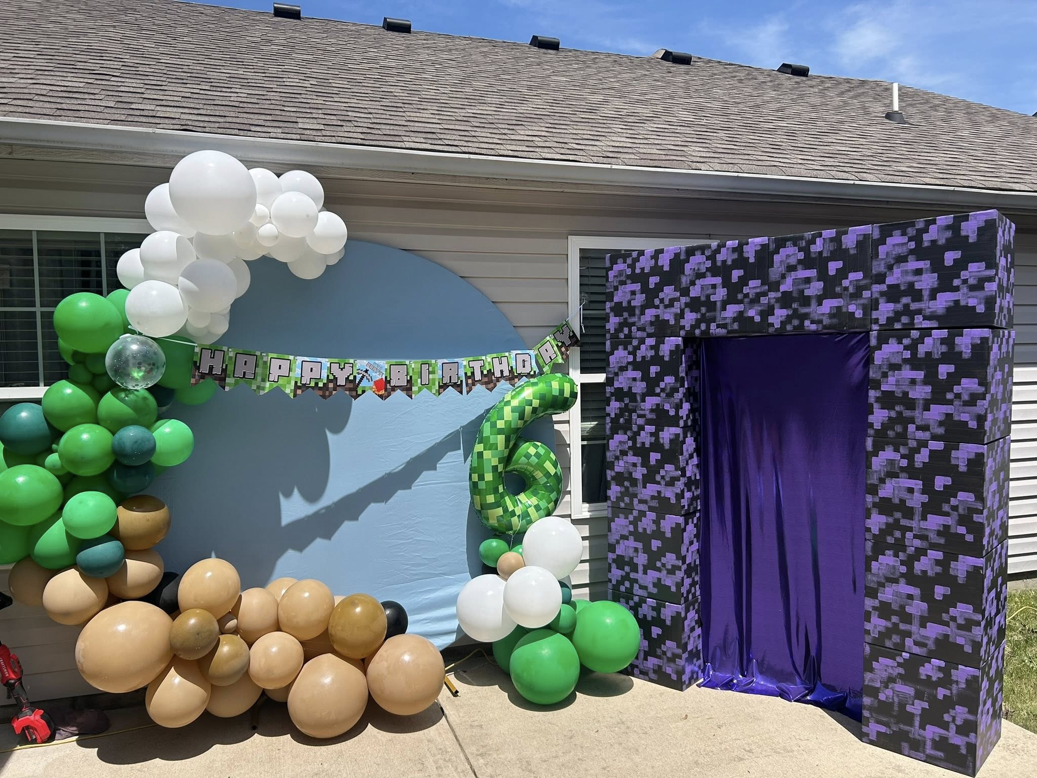 Minecraft-themed birthday party decorations featuring a festive balloon arch and a purple pixel art portal.