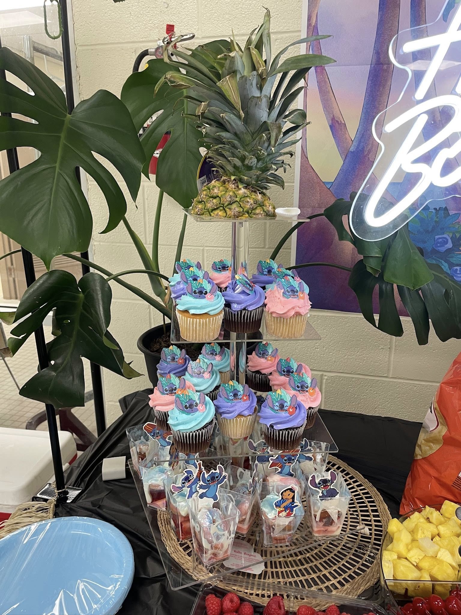 Three-tiered display of cupcakes decorated with blue and pink frosting and Lilo and Stitch character toppers