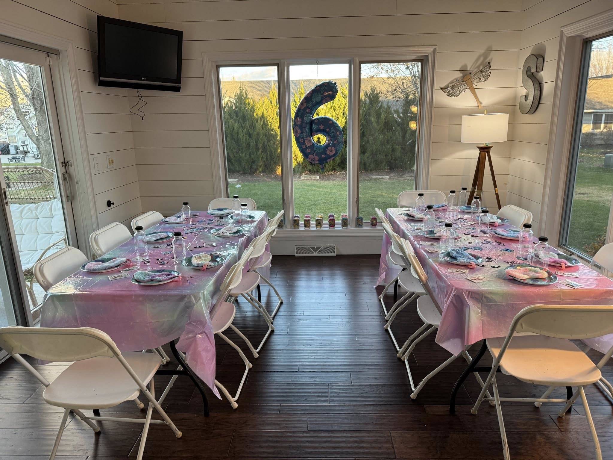 Dining tables set for a sixth birthday party with pink and purple iridescent tablecloths
