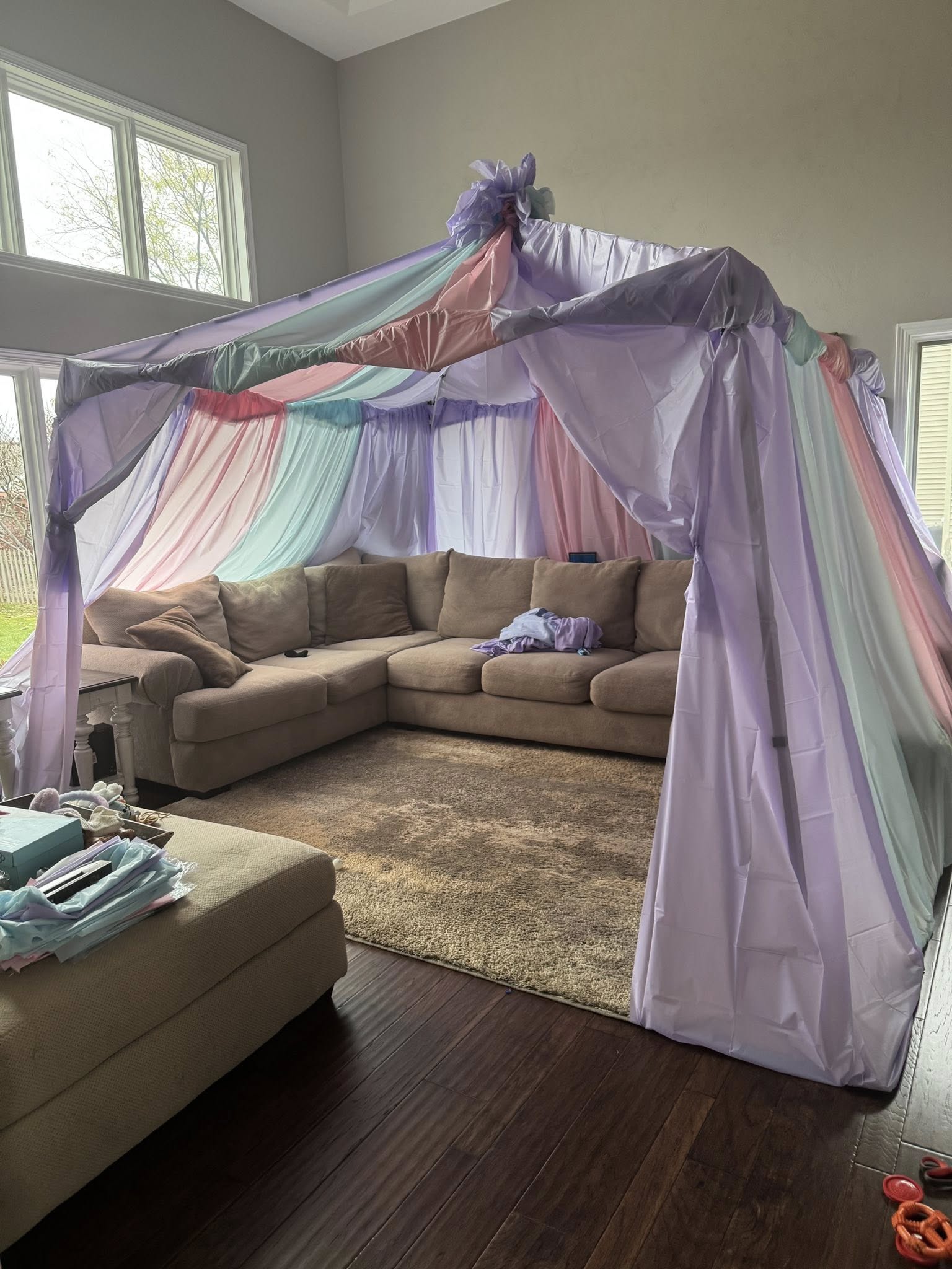 Pastel colored play tent fabric draped over a living room sectional sofa
