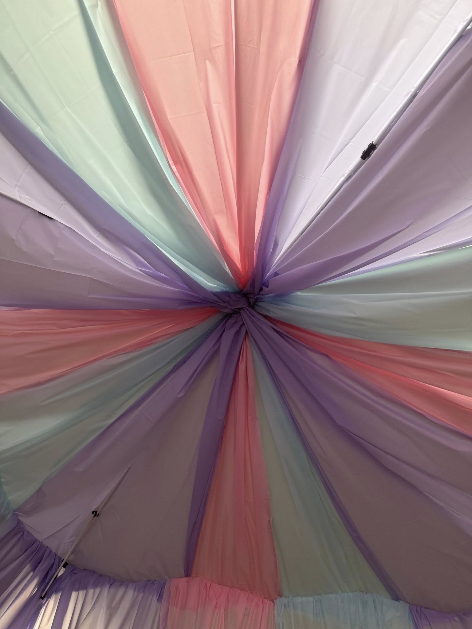 Pastel pink, purple, and mint green fabric gathered at the center of a ceiling tent canopy.