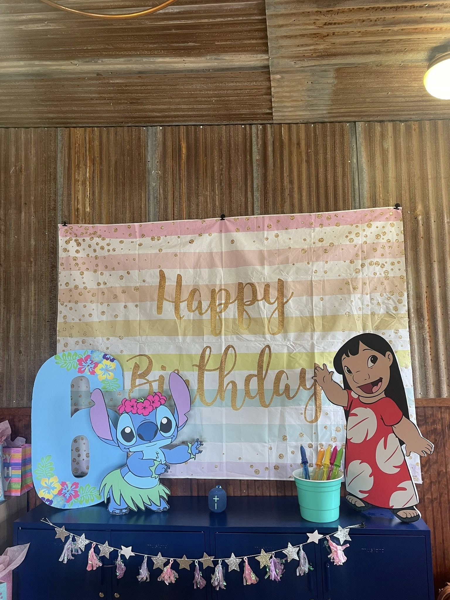 Stitch and Lilo themed 6th birthday party decoration backdrop with pastel stripes and gold glitter.