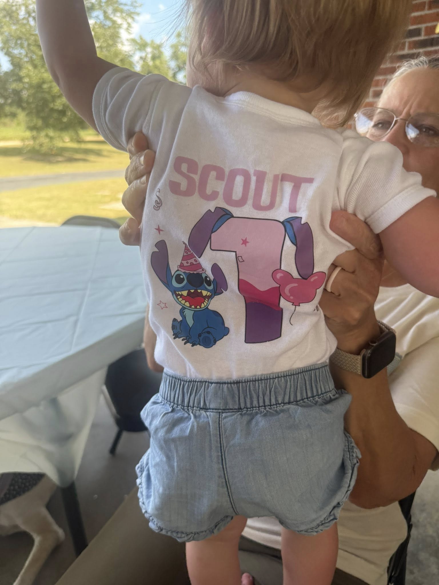 Custom baby white t-shirt featuring a first birthday design with Stitch wearing a party hat and the name Scout