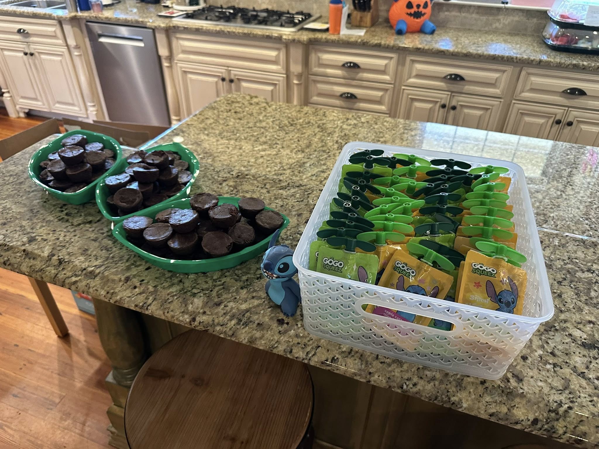 Three green bowls filled with chocolate muffin bites next to a clear bin filled with GoGo squeeZ fruit pouches.
