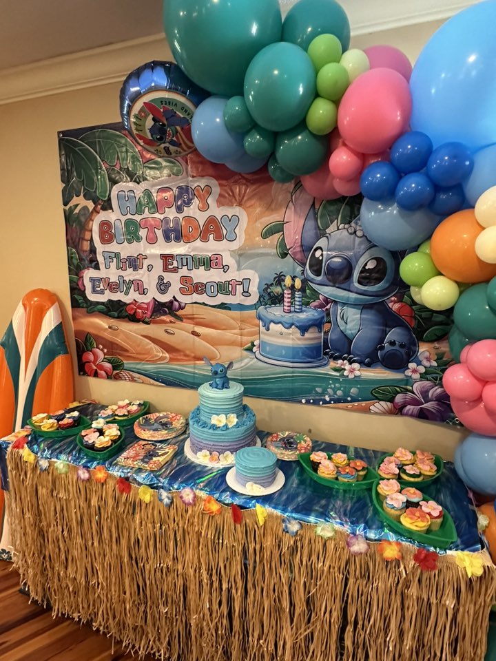 Stitch themed birthday party display with blue tiered cakes and cupcakes against a personalized happy birthday backdrop.