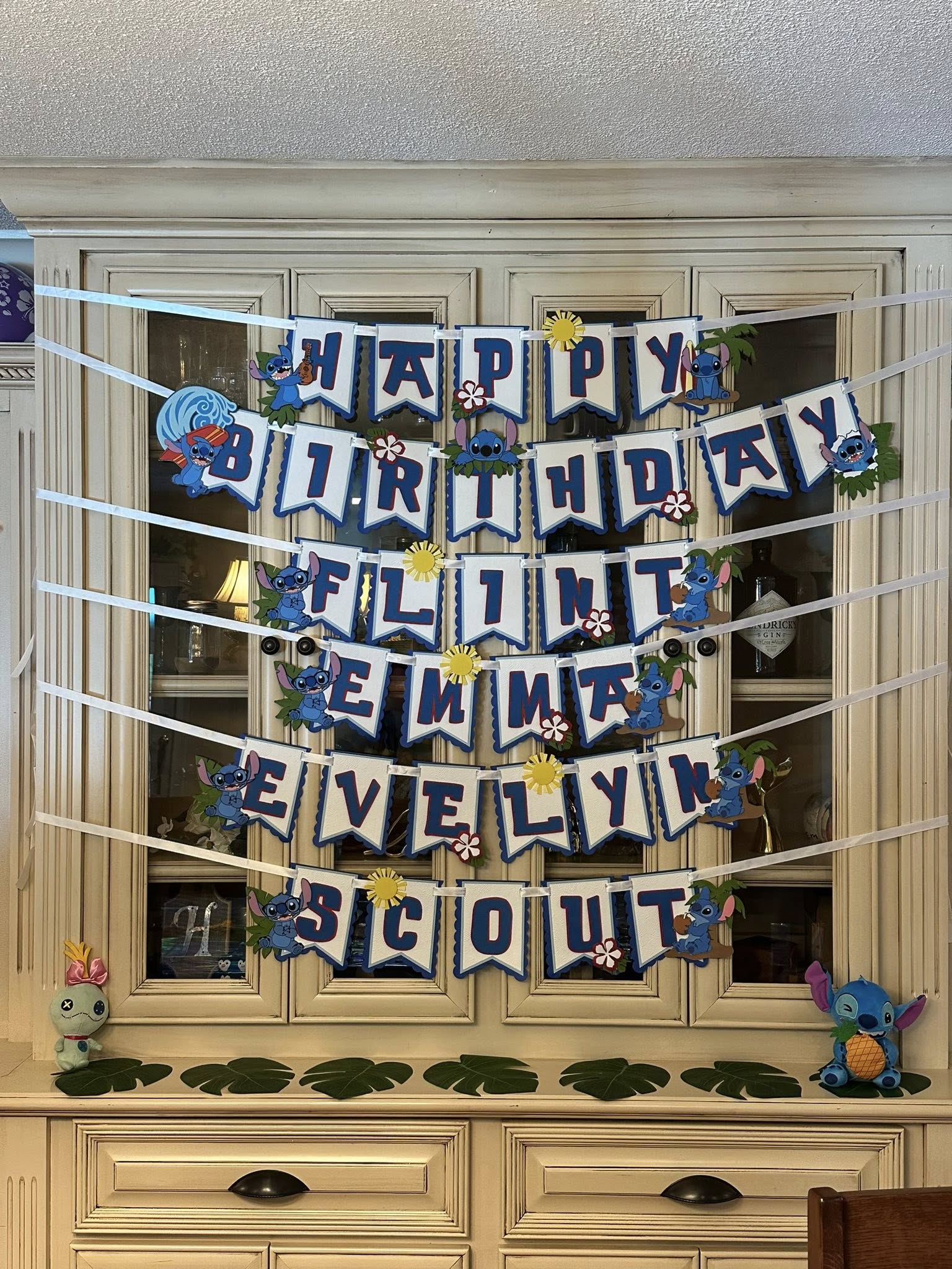 Custom Stitch-themed birthday party banner displaying Happy Birthday with names Flint, Emma, Evelyn, and Scout.