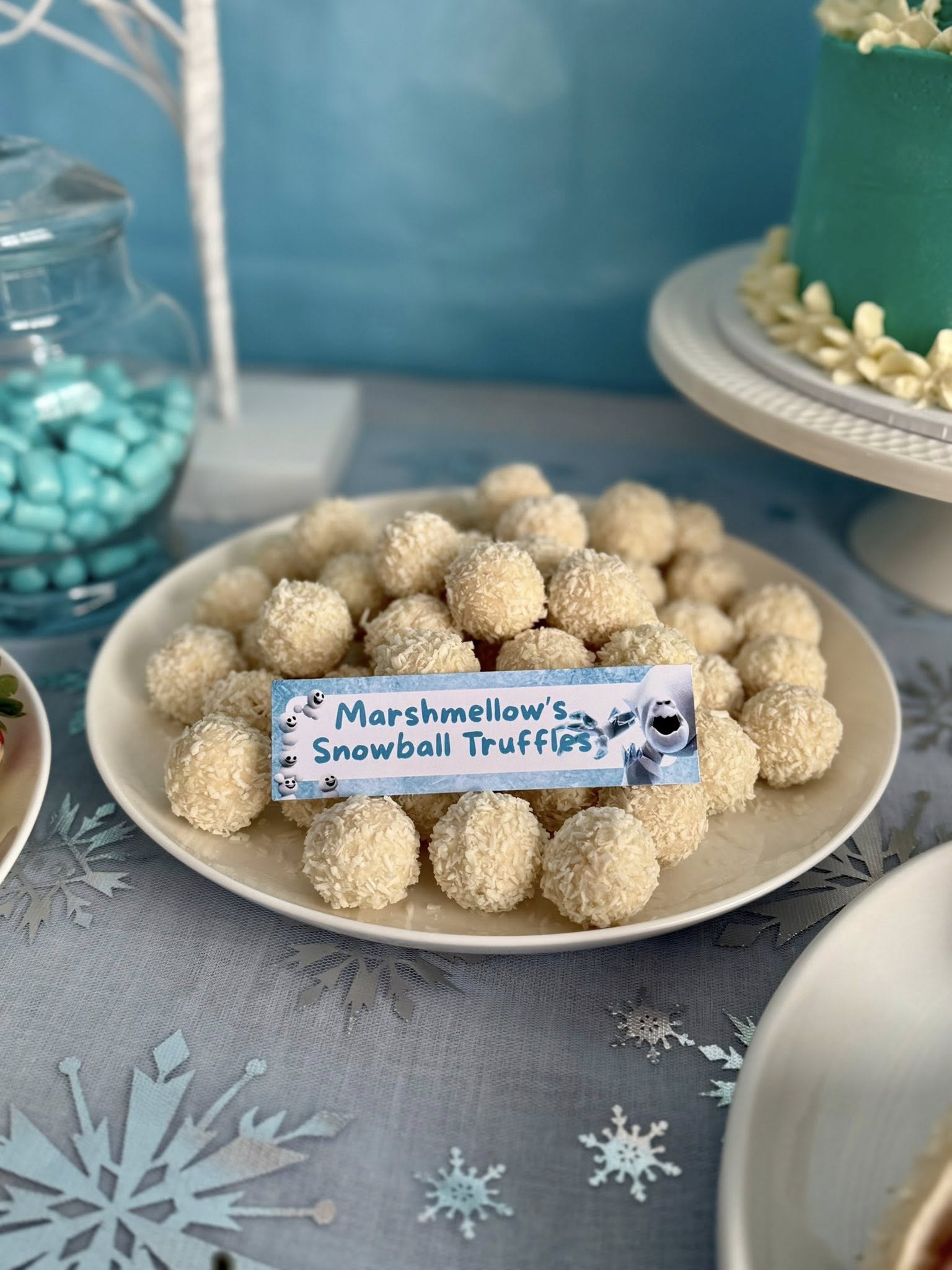 A plate of coconut-covered snowball truffles with a label reading Marshmellow's Snowball Truffles.