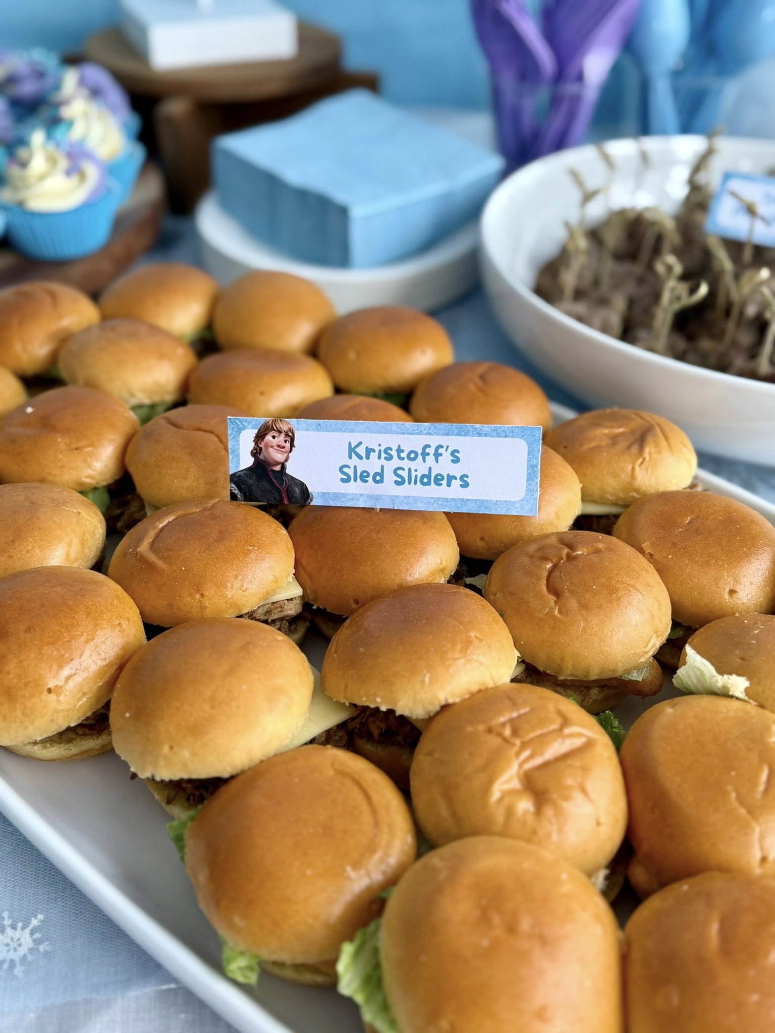 Platter of small sliders labeled Kristoff's Sled Sliders with a Frozen themed sign.