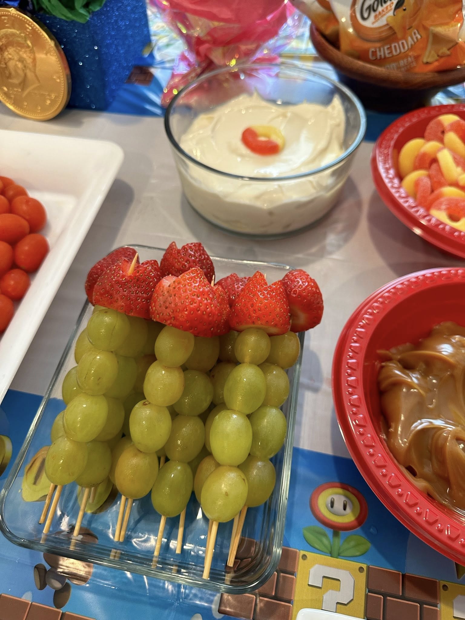 Skewers of green grapes topped with fresh strawberries in a glass dish