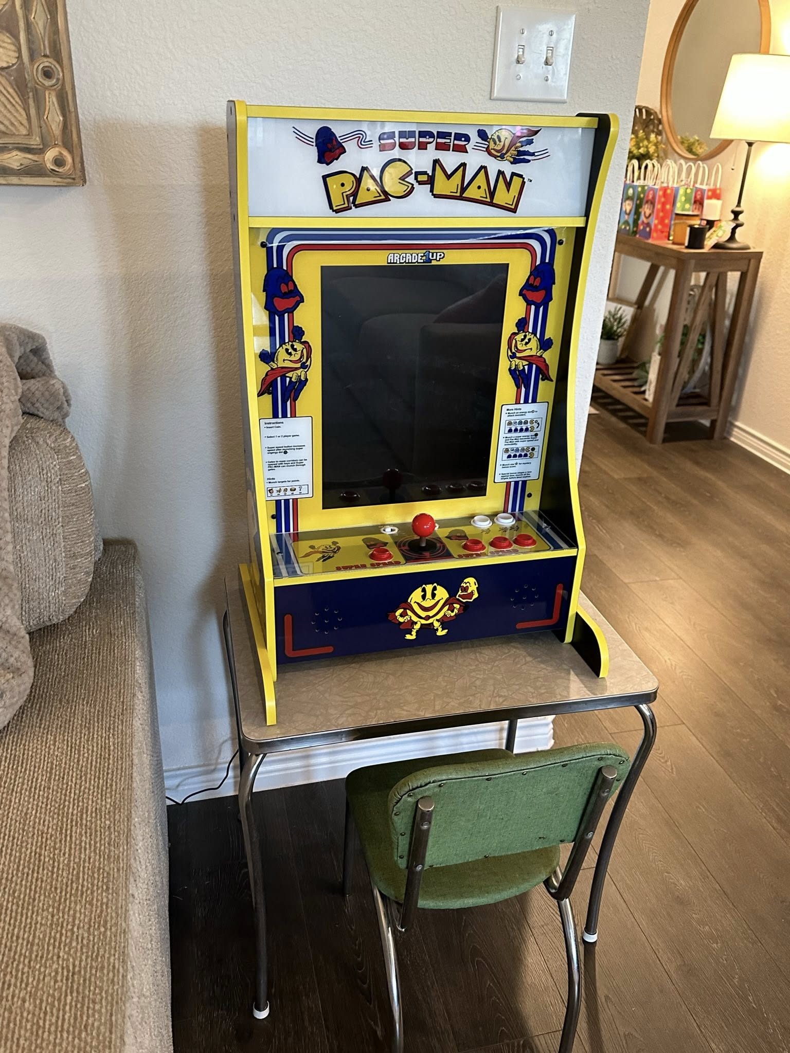 Super Pac-Man Arcade1Up countertop cabinet on a small table with a green chair